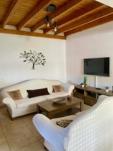 a living room with two white couches and a flat screen tv at BAREFOOT COTTAGE in Skiathos