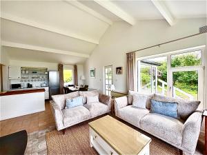 a living room with two couches and a kitchen at Sandy Gardens House, Lettergesh Beach in Gowlaun