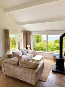 a living room with two couches and a large window at Sandy Gardens House, Lettergesh Beach in Gowlaun
