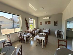 a restaurant with tables and chairs and a large window at Hotel Tropical in Aquidauana