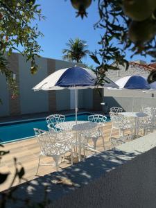 a table and chairs with an umbrella next to a pool at Hotel Tropical in Aquidauana
