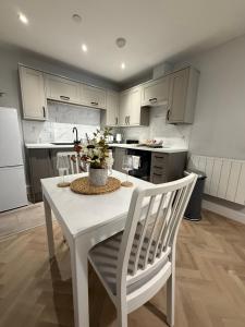 a white kitchen with a white table and chairs at The Loft Town Centre in Merthyr Tydfil +22 photos
