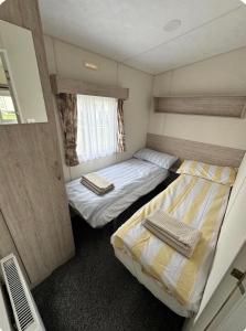 two beds in a small room with a window at Brand New Caravan in Selsey