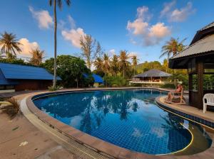 a woman sitting in a chair next to a swimming pool at Nirvana By the Sea in Ban Madua Wan