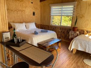 a bedroom with two beds and a table and a window at Departamentos Eldestino in Puerto Puyuhuapi