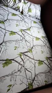 a bed with a white comforter with leaves on it at Best White House Hotel in Umunede