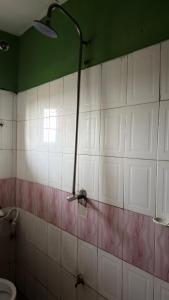 a bathroom with a shower and a white tiled wall at Best White House Hotel in Umunede