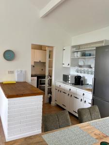 a kitchen with white cabinets and a black refrigerator at Sandy Gardens House, Lettergesh Beach in Gowlaun