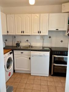 a kitchen with white cabinets and a white dishwasher at Sandy Gardens House, Lettergesh Beach in Gowlaun +19 photos