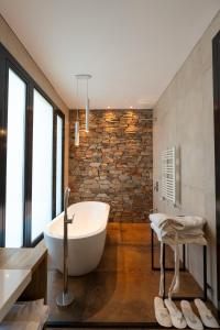 a bathroom with a white tub and a brick wall at Casa Reserva jacuzzi Climatizado, Diseño y Naturaleza en Chacras de Coria in Ciudad Lujan de Cuyo +95 photos