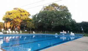 an empty swimming pool with white chairs and trees at HaKaron in Ein HaBesor