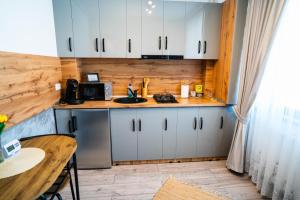 Eine Küche mit weißen Schränken, einem Tisch und einer Spüle in der Unterkunft Sofia Residence Studio Cetate in Târgu Neamţ