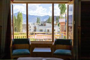a window with two chairs and a view of a city at Chandan Guest House in Leh