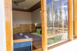 a small bedroom with a bed and a balcony at Chandan Guest House in Leh