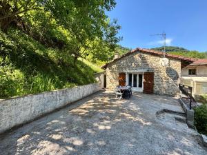 a stone house with a table and chairs in front of it at Le petit repère in Jujurieux +5 photos