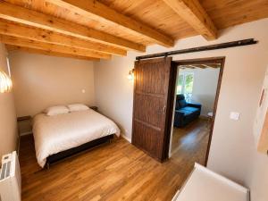 a bedroom with a bed and a couch and wooden ceilings at Le petit repère in Jujurieux