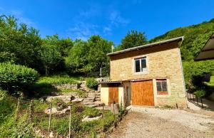 a small brick building with a door on a hill at Le petit repère in Jujurieux