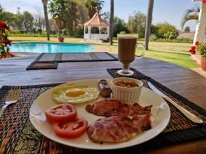 a plate of food with eggs and tomatoes and a drink at Villa Sardinia Guest House in Midrand