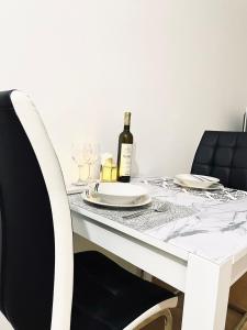 a white table with a bottle of wine and glasses at Apartman LUXE STAY Vujović in Bileća