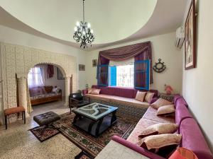 a living room with a purple couch and a table at Villa cleopatra in Mezraya