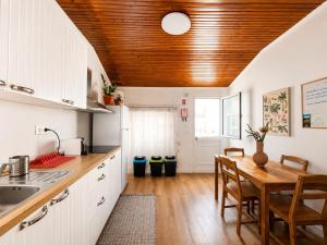 a kitchen with white cabinets and a wooden ceiling at Botânico Guesthouse in Nordeste