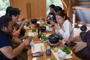 a group of people sitting around a table eating food at 囲み宿 こわね in Tonosho