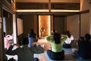 a group of people sitting in a room watching a woman doing yoga at 囲み宿 こわね in Tonosho