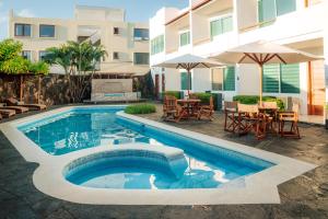 a swimming pool with a table and chairs and a building at Hotel Ninfa in Puerto Ayora