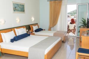 a hotel room with two beds and a balcony at Sunrise Beach Hotel in Ammoudia