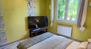 a bedroom with a flat screen tv and a bed at Samedi soir au calme in Val De Livre