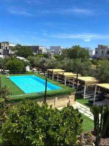 a large swimming pool with tables and umbrellas at CH Guest House in Vernole