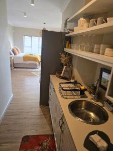 a kitchen with a sink and a room with a bed at Still in Struisbaai