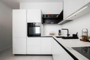 a kitchen with white cabinets and a black microwave at Apartma Svetlo udobje v Piranu - Bright Comfort Apartment in Piran in Piran