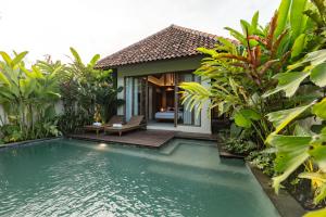 a villa with a pool in front of a house at Apittoya Villas in Gianyar