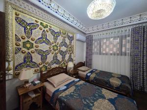 a bedroom with two beds and a wall covered in tiles at Gulnaraxanum Boutique Hotel Premium in Bukhara