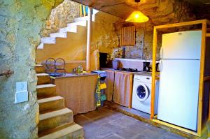 a kitchen with a refrigerator and a stove and stairs at Le Mazet d'Aurore in Chassiers