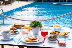 a table with breakfast food next to a swimming pool at Sunrise Beach Hotel in Ammoudia