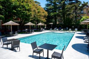 a swimming pool with chairs and tables and umbrellas at Hotel Clelia in Deiva Marina