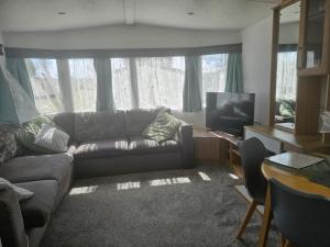 a living room with a couch and a television at 3 bed static van with decking in Dymchurch