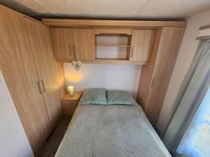 a small room with a bed and wooden cabinets at 3 bed static van with decking in Dymchurch +16 photos