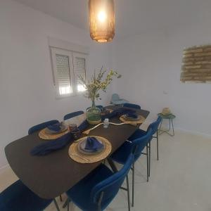 a dining room table with blue chairs and a table with hats at Casa de angil in Tivenys