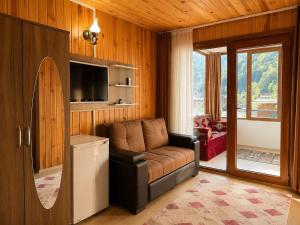a living room with a leather couch and a television at Şekersu Otel in Çaykara