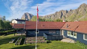a blue house with a red roof with mountains in the background at Damveien 1-Apartment in Bleik