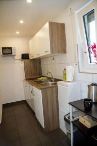 a small kitchen with white cabinets and a sink at Apartment für 3, 2 Boxspringbetten, Internet & Parkplatz in Dortmund