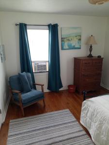 a bedroom with a blue chair and a window at Binghamton Studio in Binghamton
