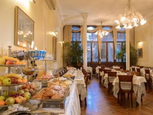 un restaurante con mesas y sillas con comida a la vista en Centauro Hotel, en Venecia