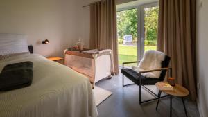 a bedroom with a bed and a chair and a window at Ferienhof Schnurrum in Emmelsbüll-Horsbüll