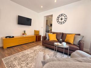 a living room with a couch and a clock on the wall at Unique Devon Cottages - Sunrise Cottage in Exmouth