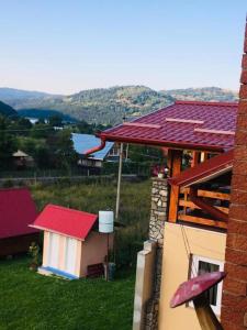 a building with a red roof on a green field at Casa Flory nr 2- Complex de Pensiuni si Casute la Munte in Bistricioara