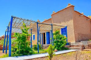 an old brick house with blue poles in front of it at Kasbah Abdou in El Kelaa des Mgouna +74 photos